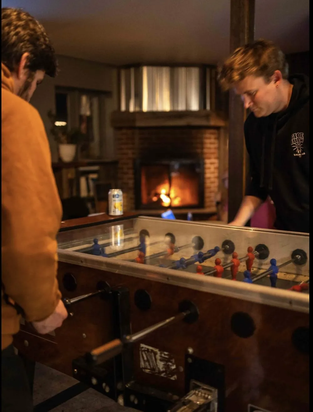 Two guests playing foosball by the fireplace