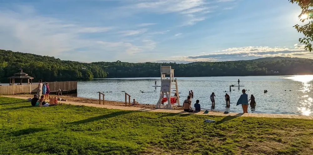 Lac Mercier beach with a lifeguard chair, swimmers and paddleboarders in the late afternoon